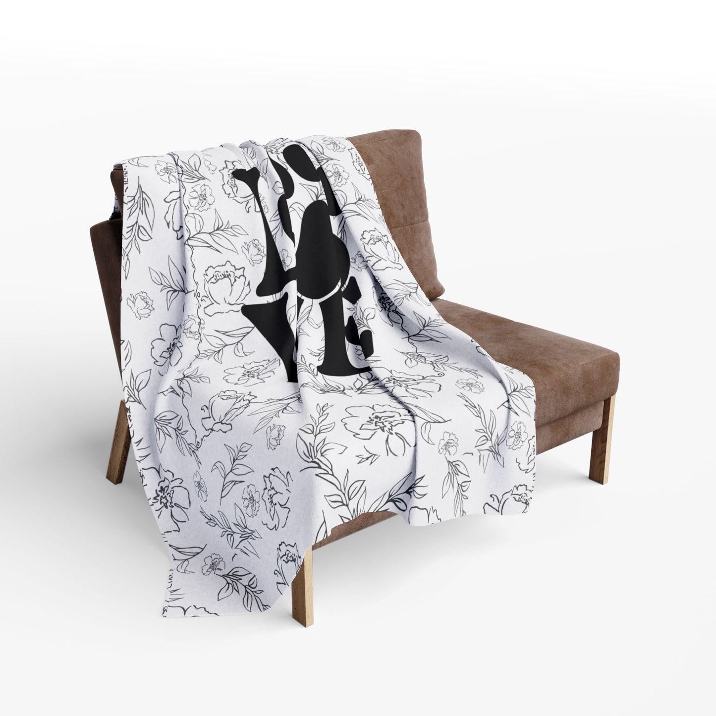 Larger size Floral patterned blanket with black silhouette design draped over a brown chair.