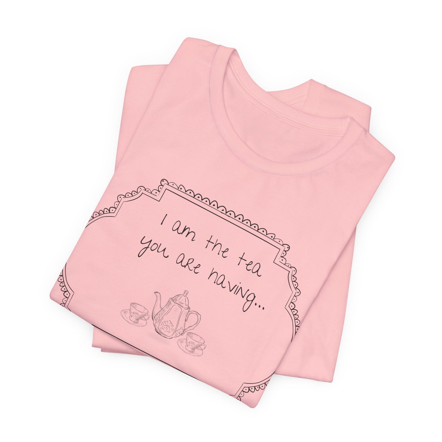 Folded pink t-shirt with tea-themed text and graphics on a white background