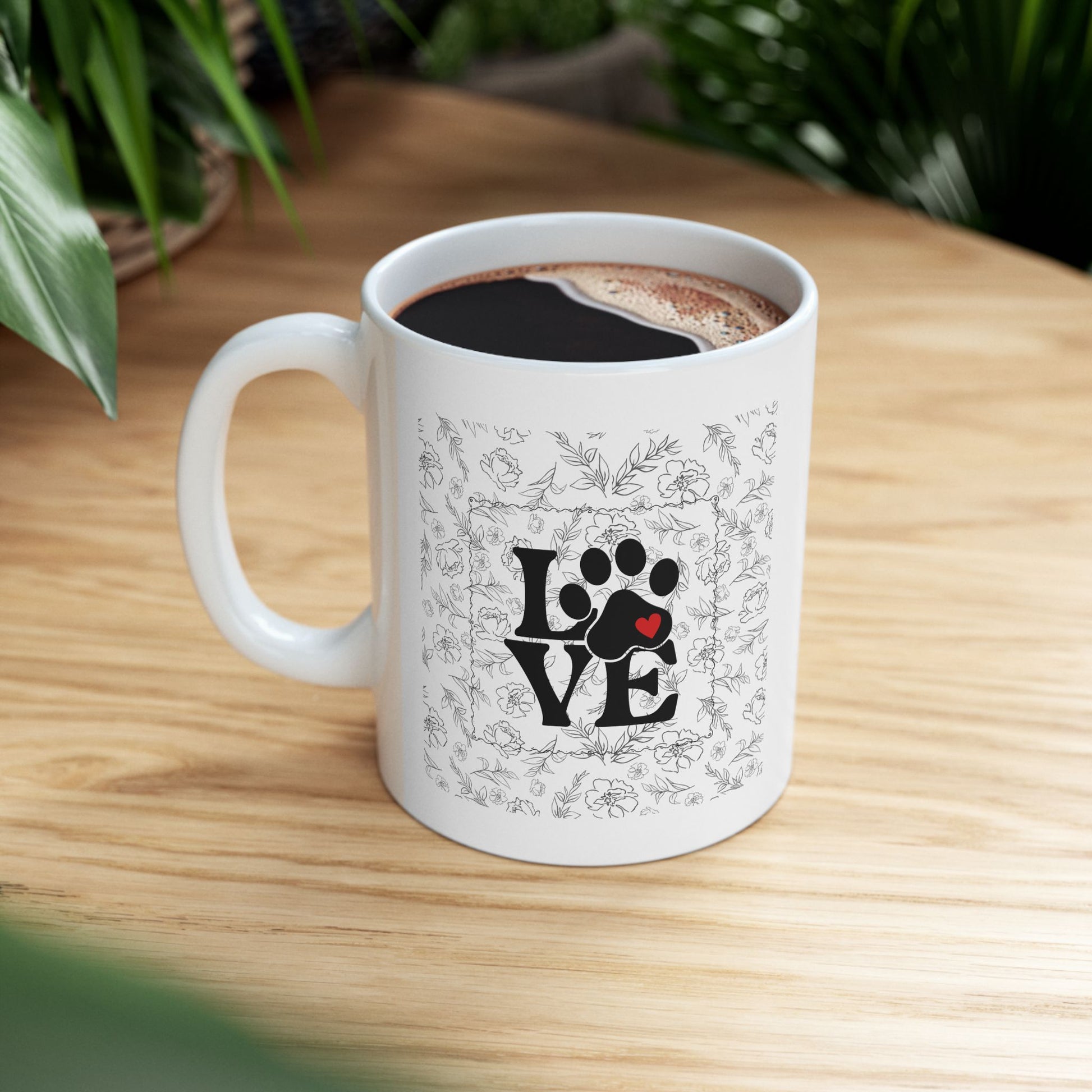 White mug with paw print design and 'LOVE' text on a wooden table.