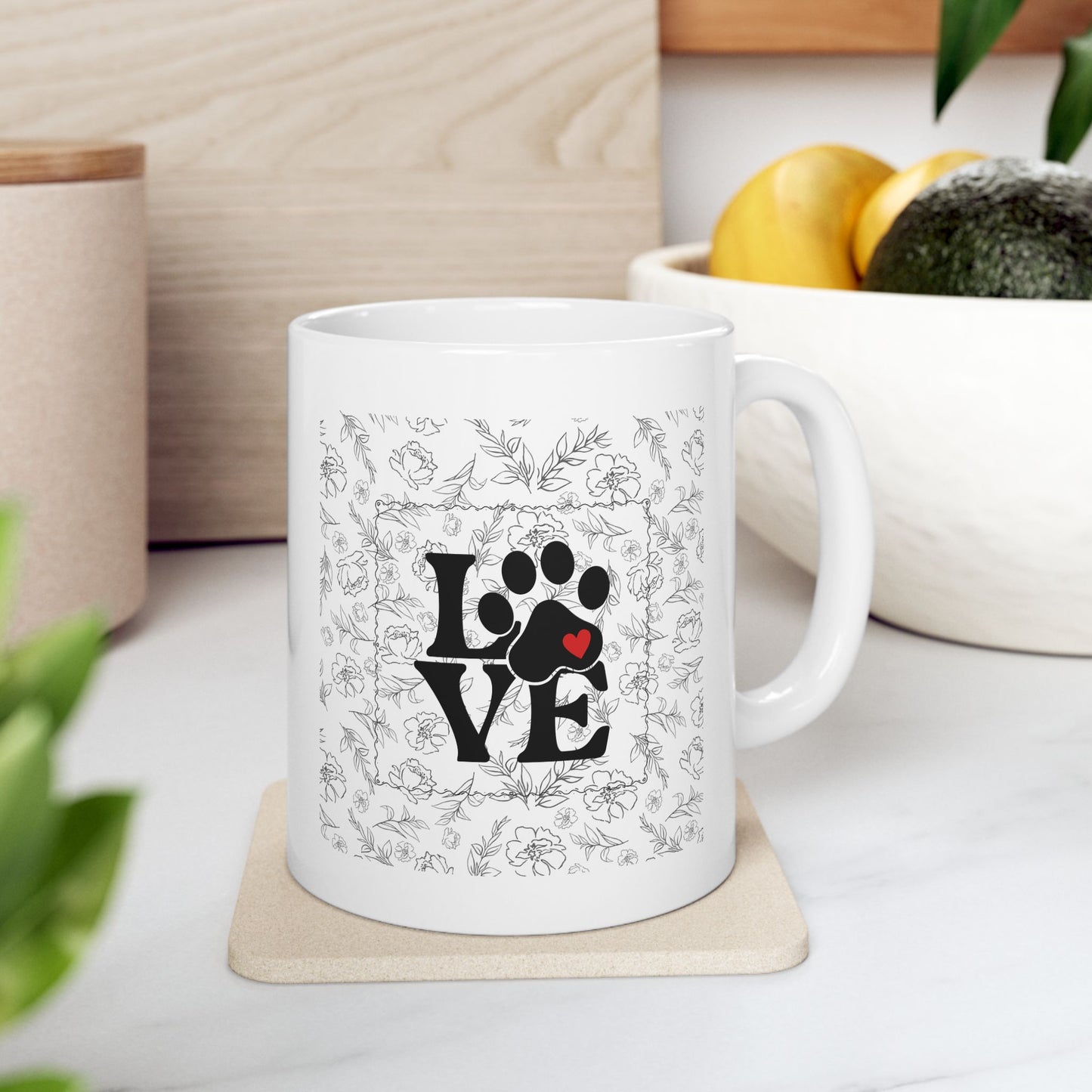 White mug with paw print and 'LOVE' design on a coaster, surrounded by decorative items.