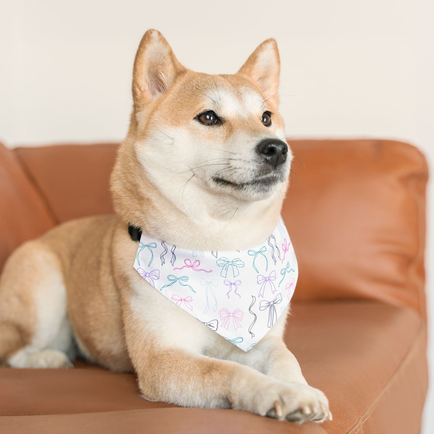 Dog wearing a bandana with a bow pattern on a brown couch