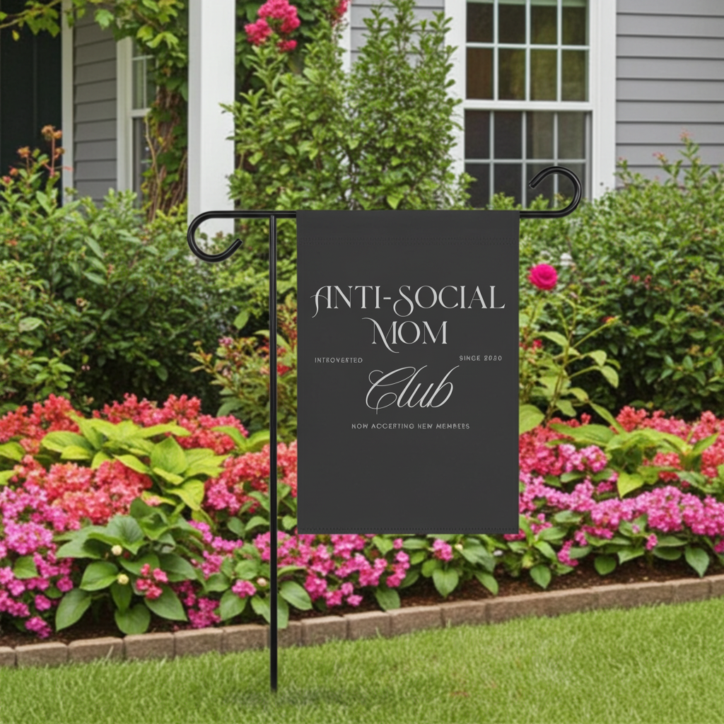 Garden flag with 'Anti-Social Mom Club' text in front of a house with flowers and bushes.